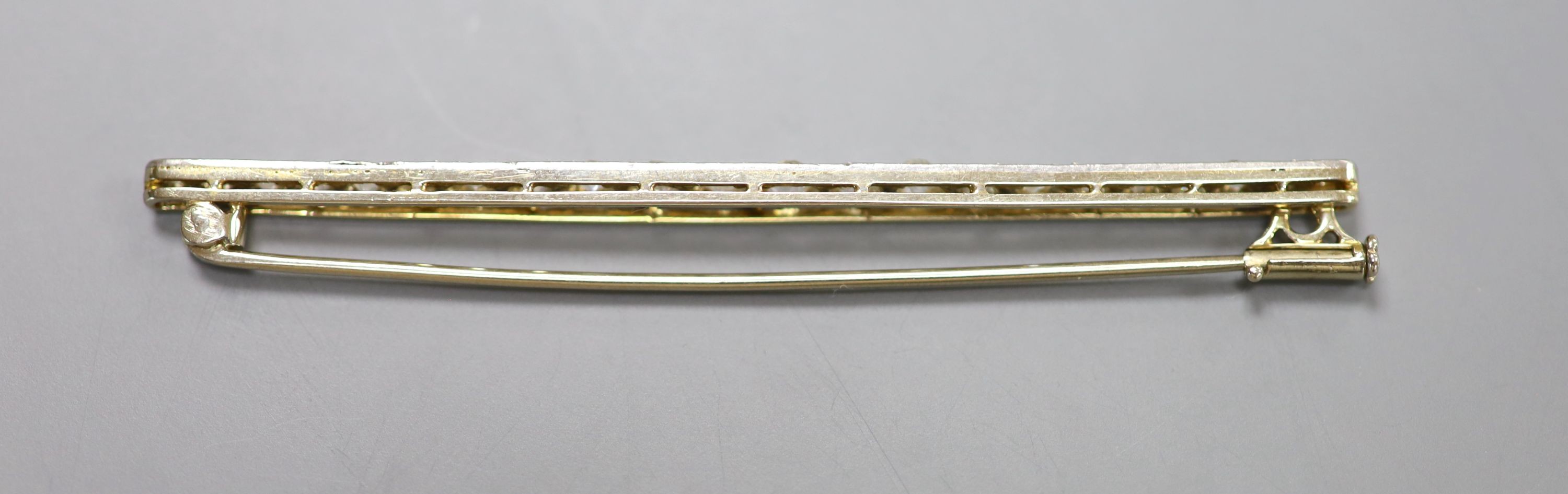 An early 20th century yellow metal and graduated twenty stone diamond set bar brooch, 67mm, 4.9 grams.